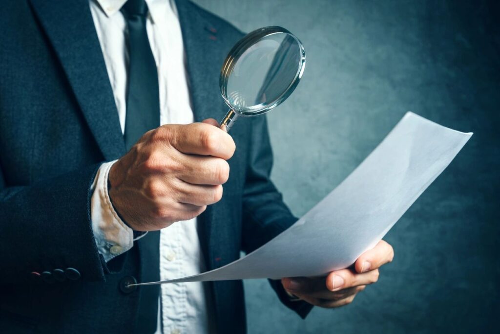 Person holding a magnifying glass over a document