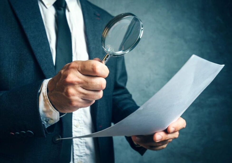 Person holding a magnifying glass over a document